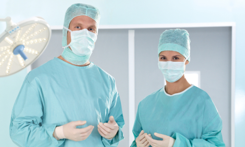 chirurgisches Team mit OP-Haube, OP-Maske, OP-Mantel und sterilen Handschuhen